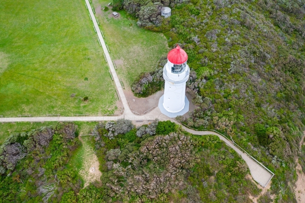 Aerial view of a white lighthouse with a red top and surrounding walking tracks - Australian Stock Image