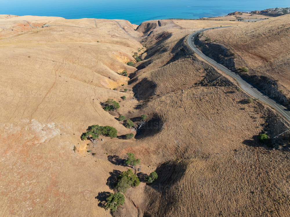 Aerial view of a winding mountain valley between dry barren hills - Australian Stock Image