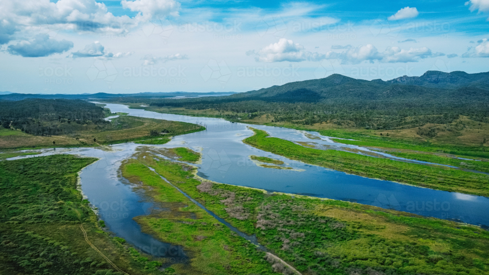 Image of Aerial view of a winding river cutting through a lush, green ...