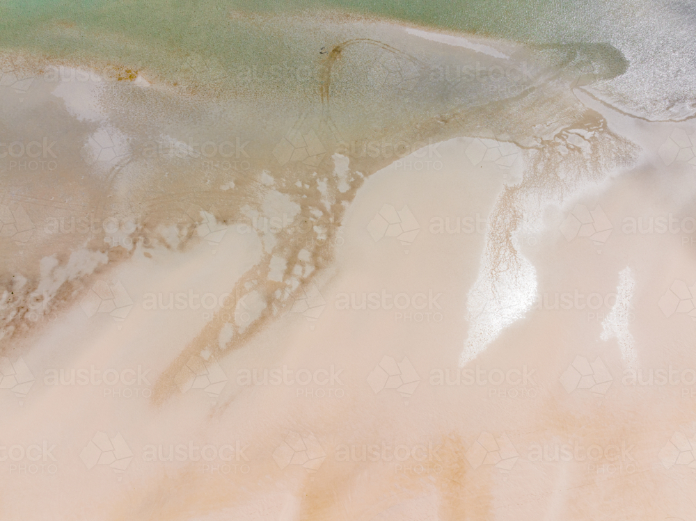 Aerial view of abstract patterns of tidal sand flats along a wide sandy beach - Australian Stock Image