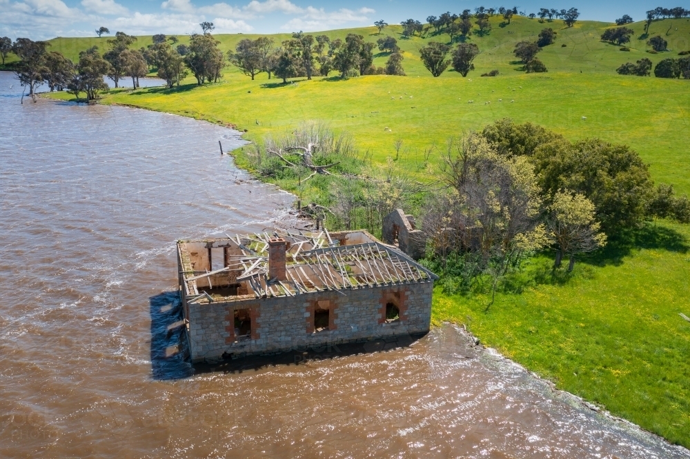 Aerial view of an abandoned historic farm house full of water on the edge of a lake - Australian Stock Image