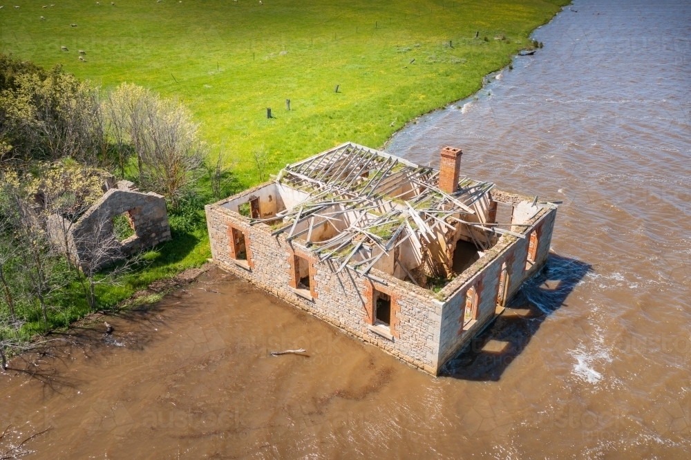 Aerial view of an abandoned historic farm house full of water on the edge of a lake - Australian Stock Image