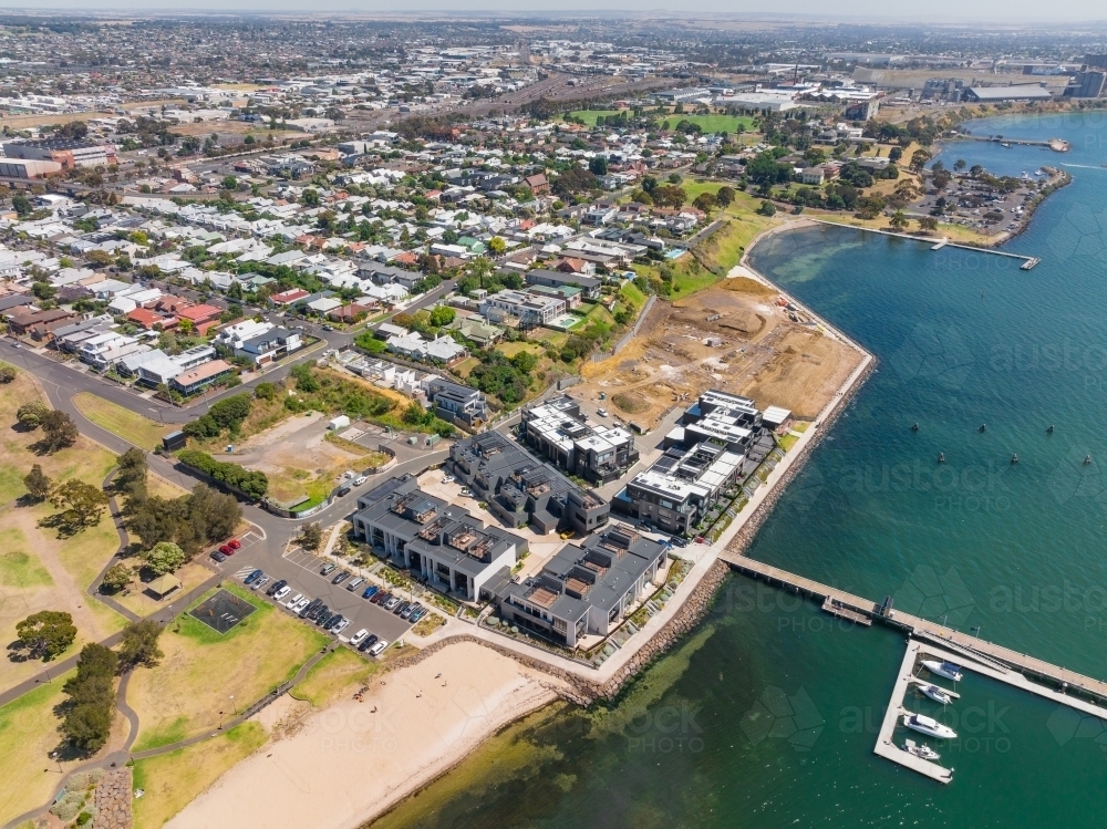 Aerial view of an apartment complex development on a coastal waterfront and suburban housing - Australian Stock Image