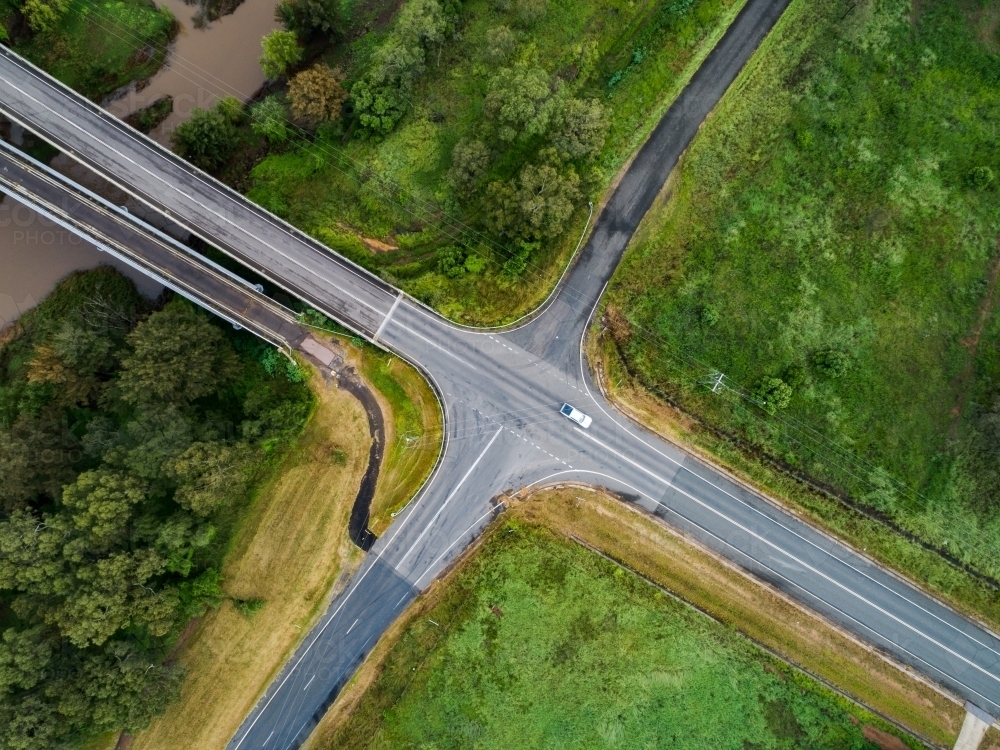 Aerial view of an open rural crossroads bordered by paddocks and hunter river with bridge over it - Australian Stock Image
