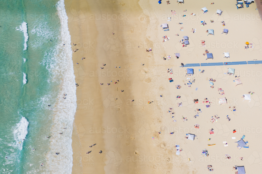 Aerial view of bathers spread over a wide sandy beach above the tide line - Australian Stock Image