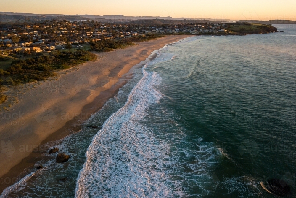 Aerial view of beach and coastal town at sunrise - Australian Stock Image