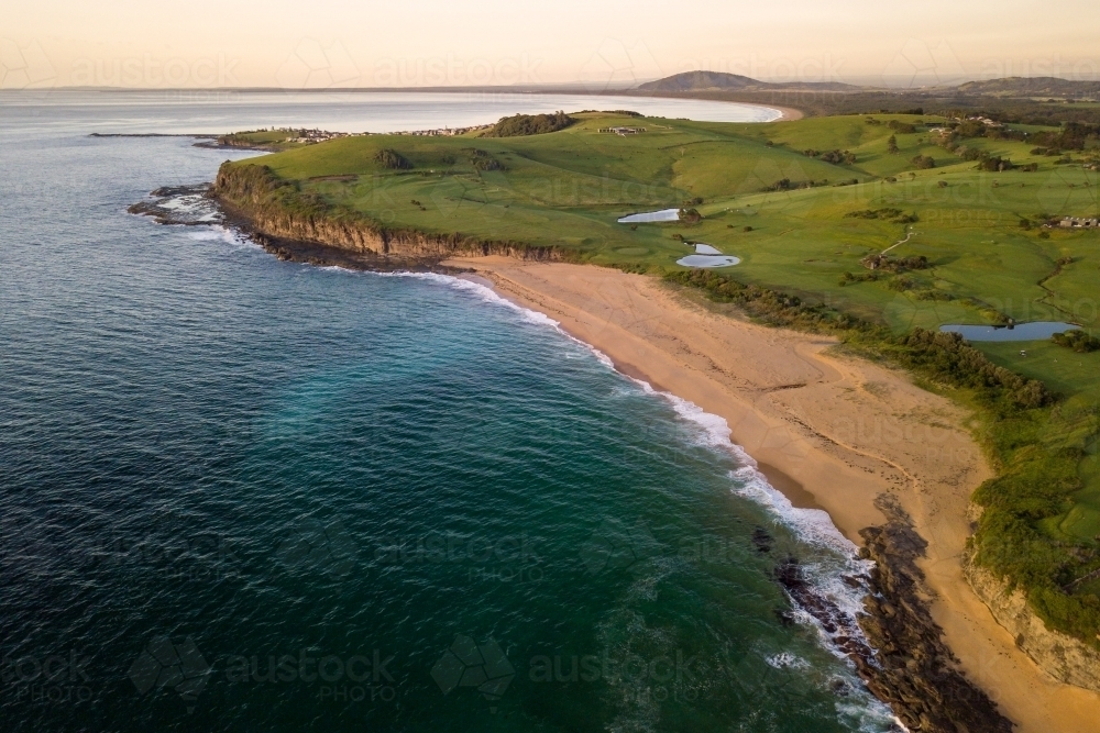 Aerial view of beached rolling green hills at sunrise - Australian Stock Image