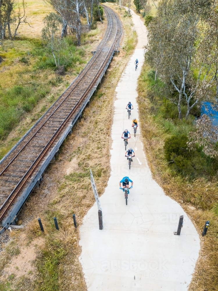 Aerial view of bicyclists racing along a path beside a railway line - Australian Stock Image