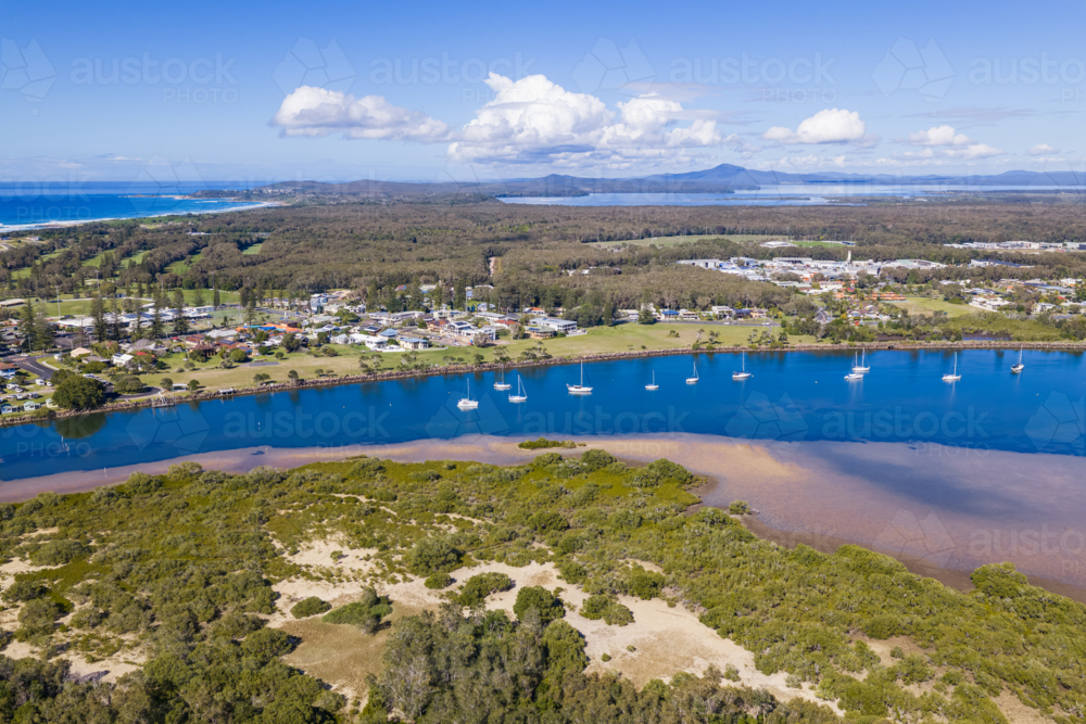 Aerial view of boats moored on the Clarence River with the coastal township of Yamba - Australian Stock Image