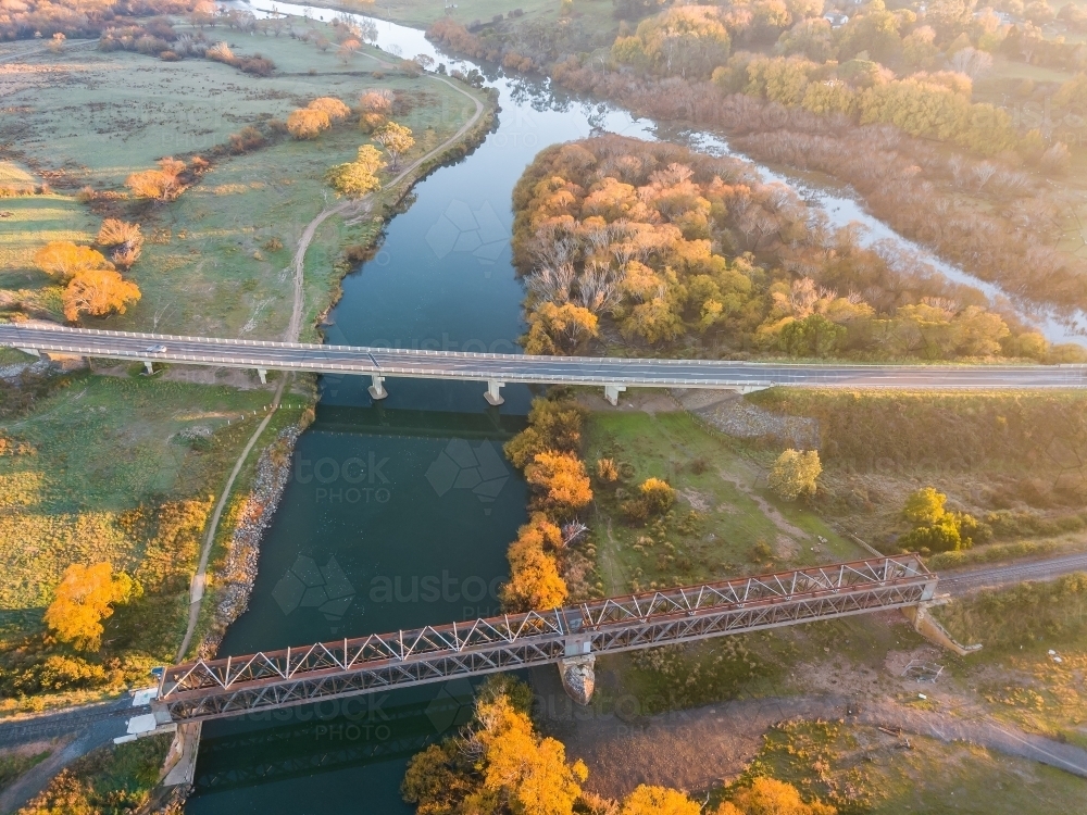 Aerial view of bridges spanning a river lined with Autumn trees - Australian Stock Image