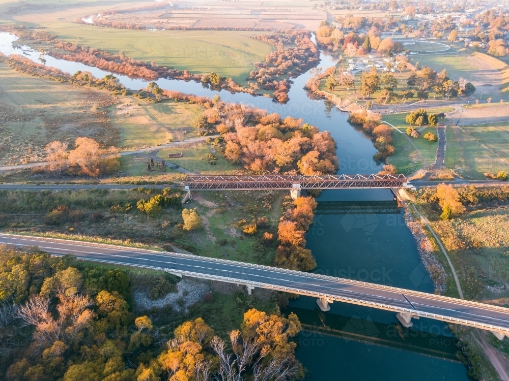 Aerial view of bridges spanning a river lined with Autumn trees - Australian Stock Image
