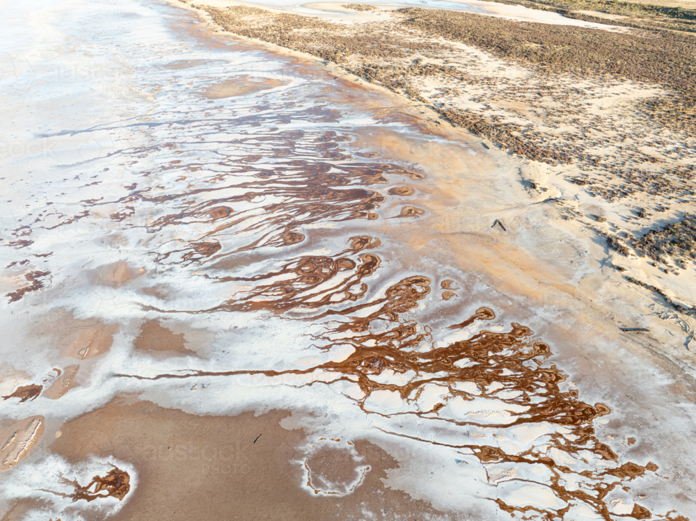 Aerial view of brown groundwater making patterns in a salt lake - Australian Stock Image