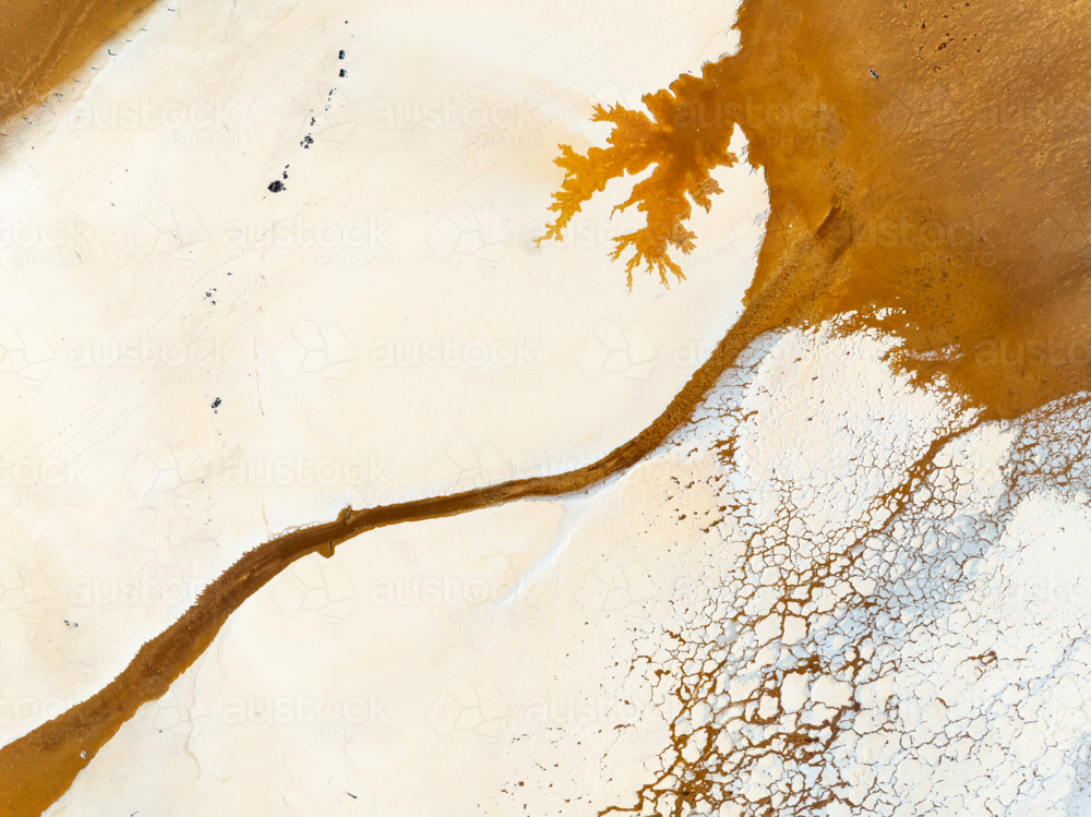 Aerial view of brown groundwater making patterns in a salt lake - Australian Stock Image