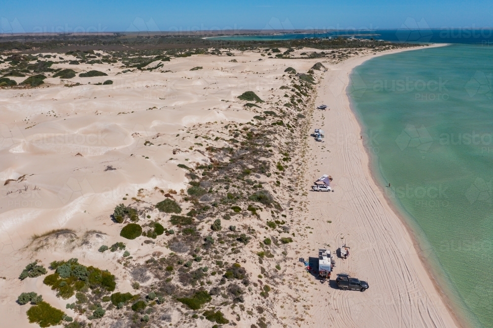 Aerial view of caravans parked on a beach in front of coastal sand dunes - Australian Stock Image