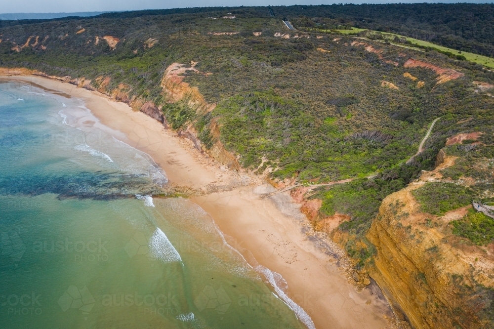Aerial view of cliffs above a deserted beach along a rugged coastline - Australian Stock Image