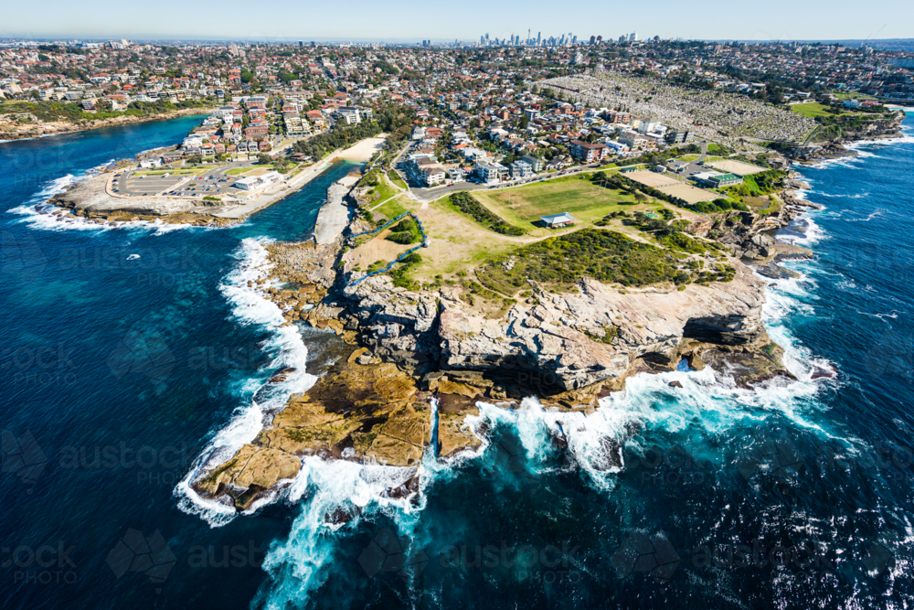 Aerial view of Clovelly coastline with waves crashing against rocky cliffs. - Australian Stock Image