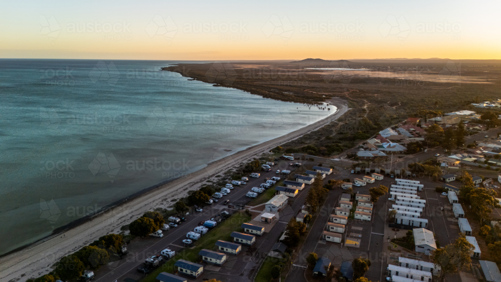 Aerial view of coastal caravan park with cabins at sunset - Australian Stock Image
