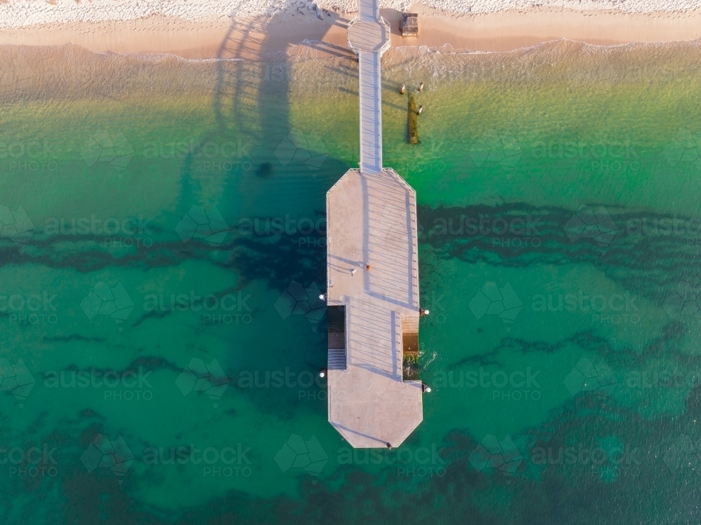 Aerial view of coastal jetty over a sandy beach and calm blue water - Australian Stock Image