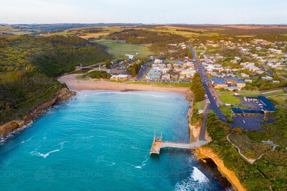 Aerial view of coastal town and jetty around a sheltered inlet and beach - Australian Stock Image