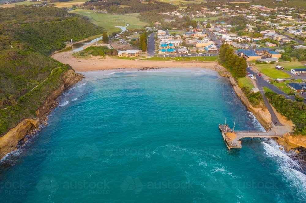 Aerial view of coastal town and jetty around a sheltered inlet and beach - Australian Stock Image