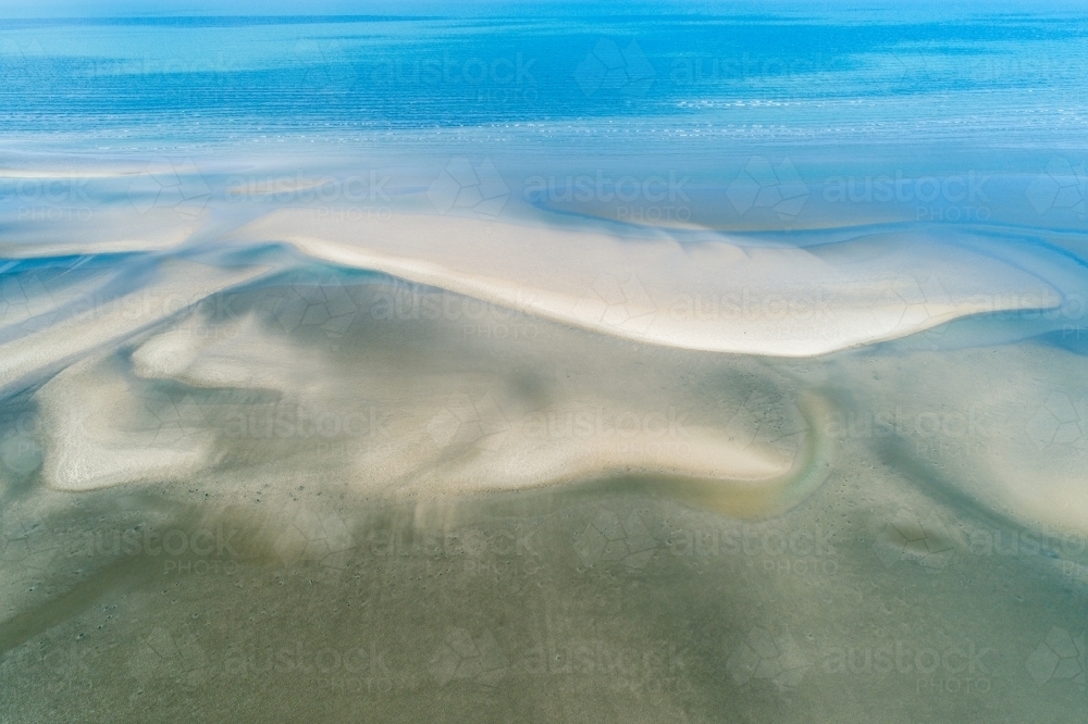 Image of Aerial view of coastline and sandbar patterns in shallow blue ...