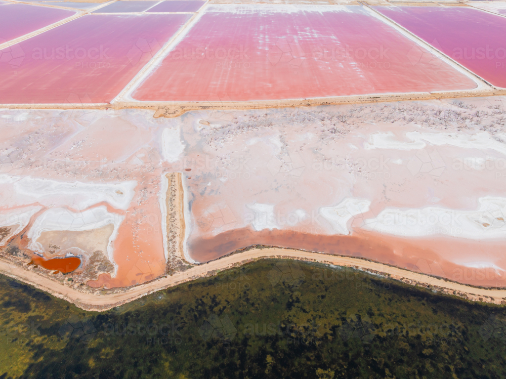Aerial view of colourful salt evaporation ponds and levee banks at a coastal salt farm - Australian Stock Image