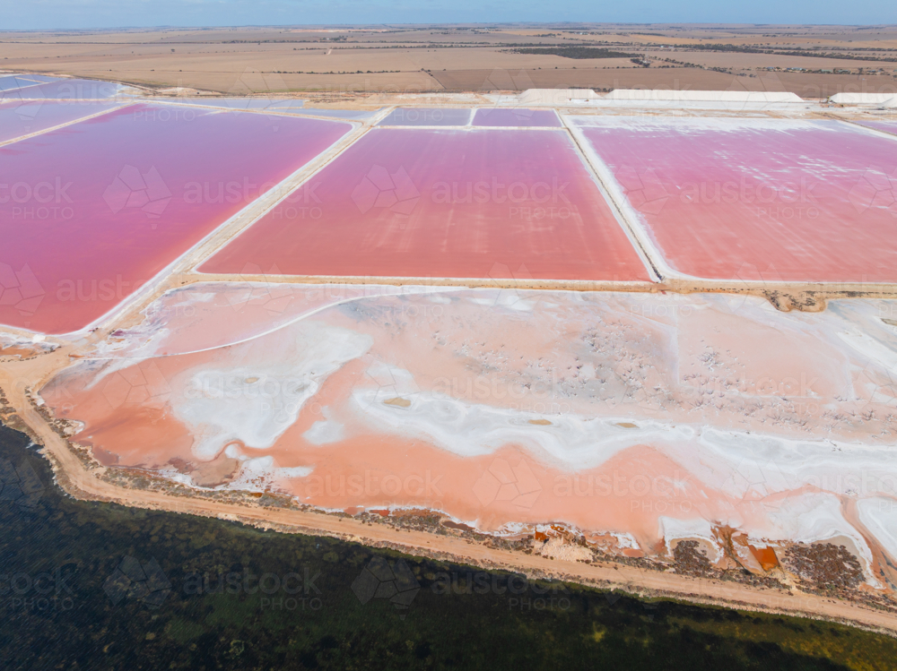 Aerial view of colourful salt evaporation ponds and levee banks at a coastal salt farm - Australian Stock Image