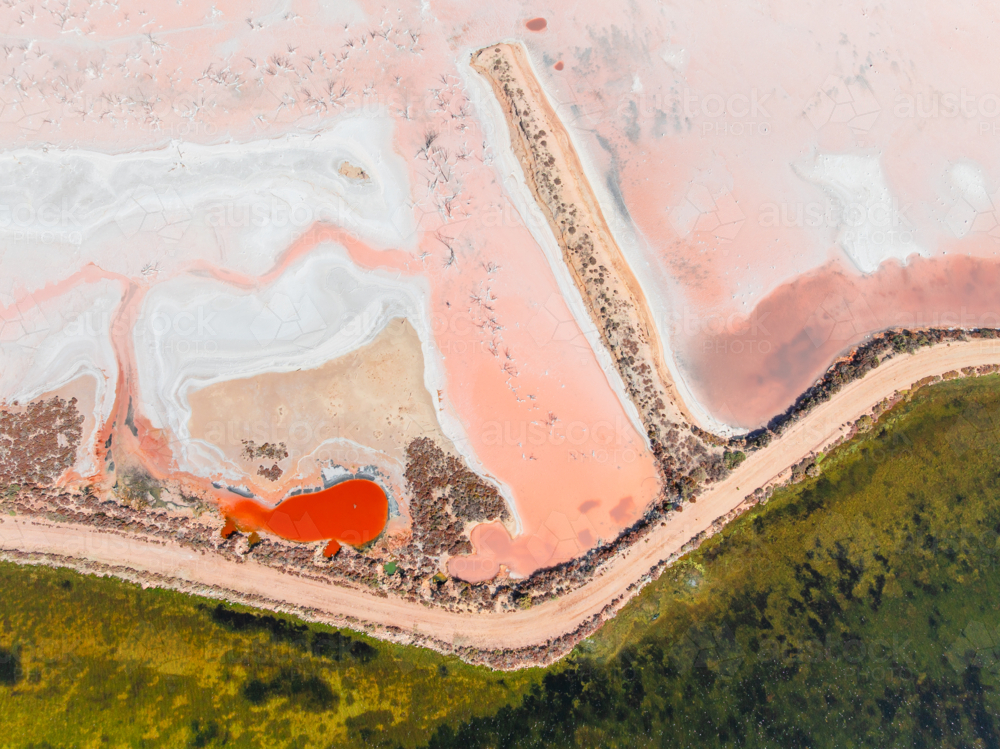 Aerial view of colourful salt evaporation ponds and levee banks at a coastal salt farm - Australian Stock Image