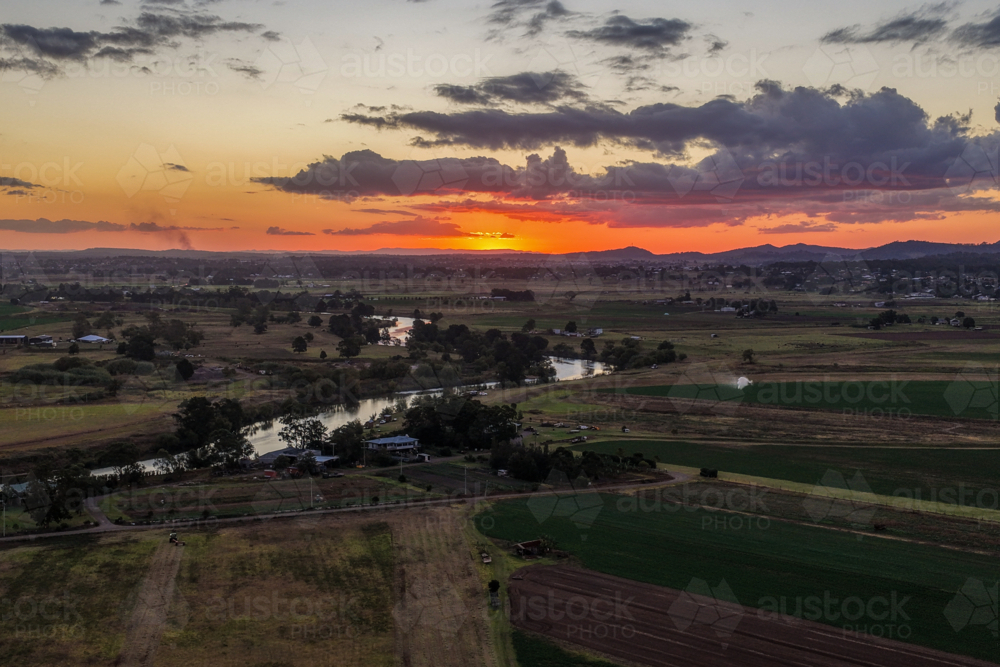 Aerial view of colourful sunset over Morpeth River and surrounding farmland at sunset - Australian Stock Image