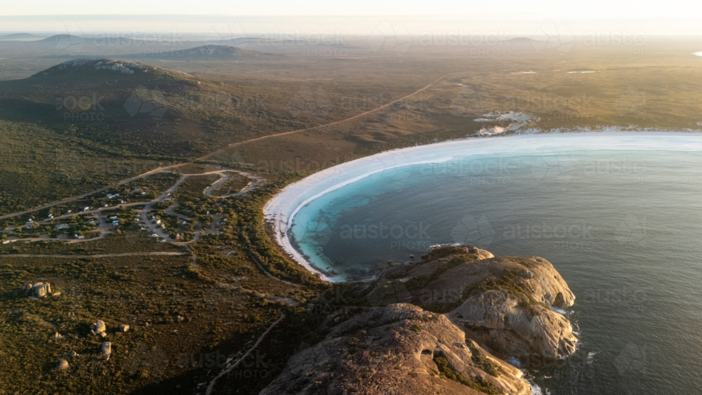 Aerial view of crescent-shaped beach at sunset - Australian Stock Image