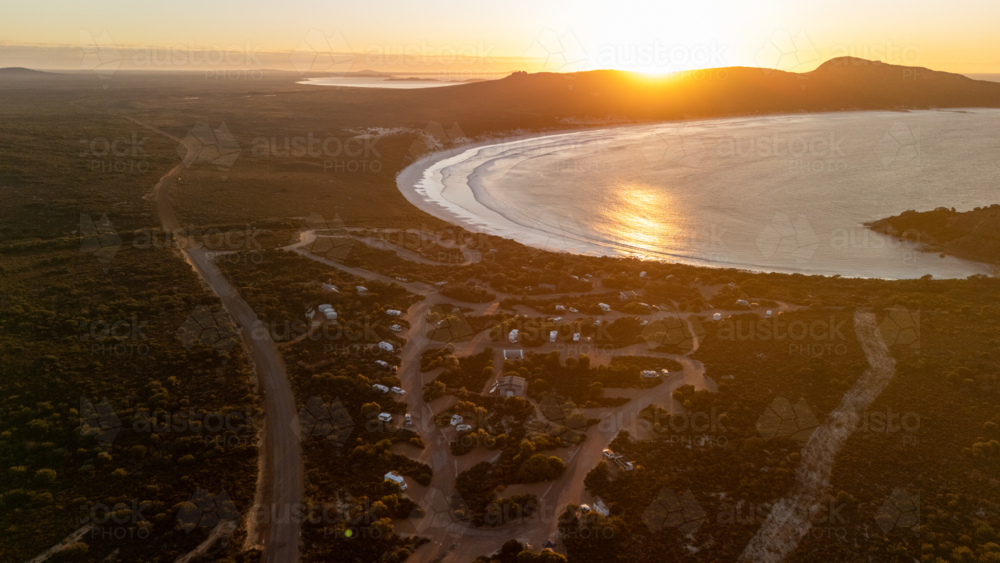 Aerial view of crescent-shaped beach at sunset - Australian Stock Image