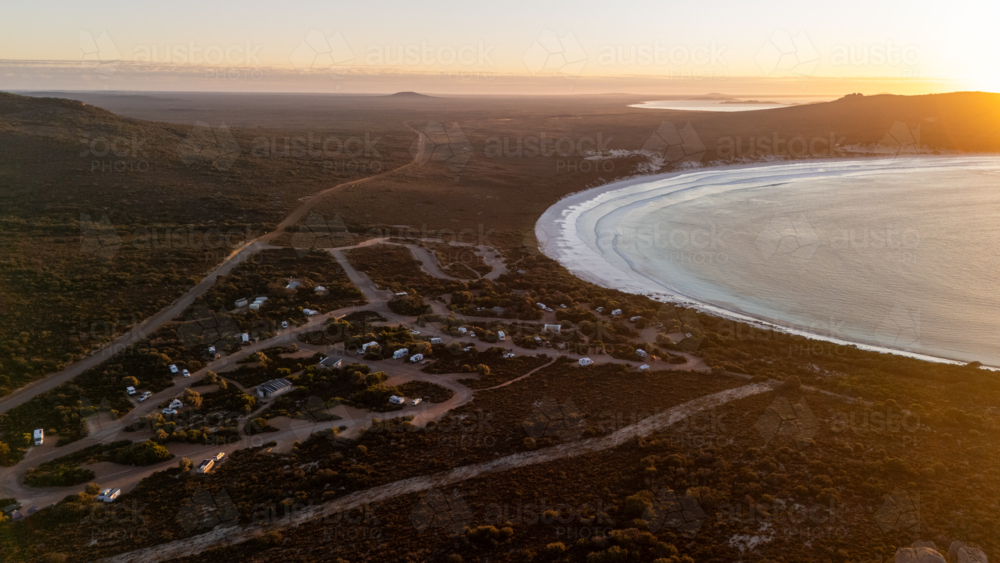 Aerial view of crescent-shaped beach at sunset - Australian Stock Image