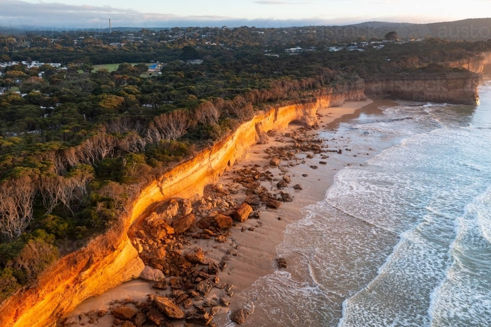 Image of Aerial view of crumbling coastal cliffs catching golden dawn ...