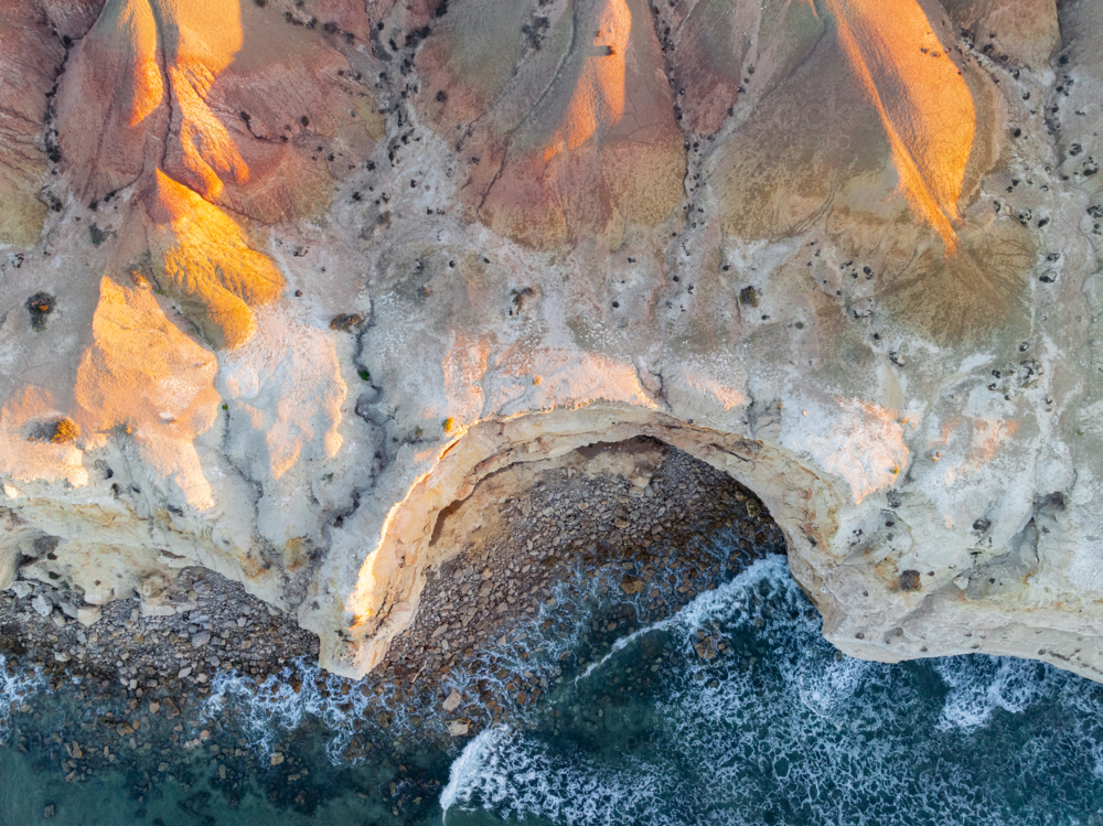 Aerial view of dramatic eroded cliff tops along a rugged coastline at sunset - Australian Stock Image