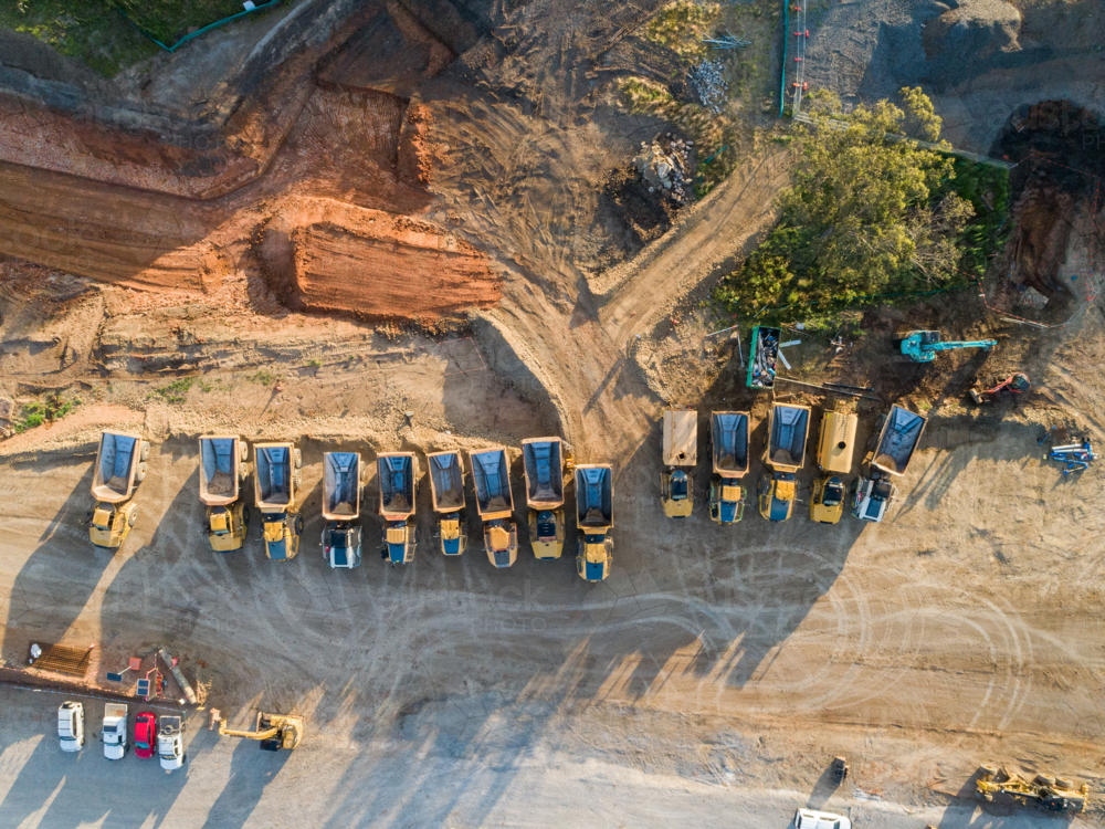 Image of Aerial view of empty dump trucks lined up on worksite in ...