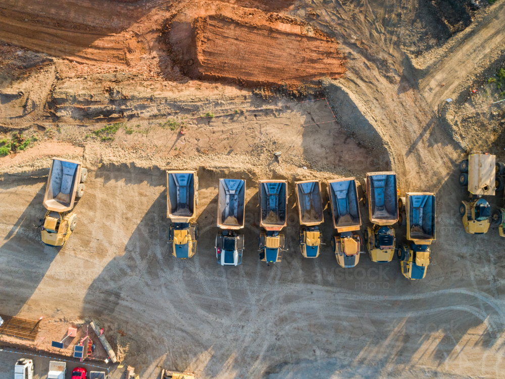 Image of Aerial view of empty dump trucks lined up on worksite in ...