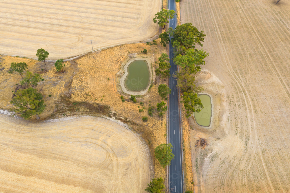 Aerial view of farm dams in dry paddocks along a country road - Australian Stock Image