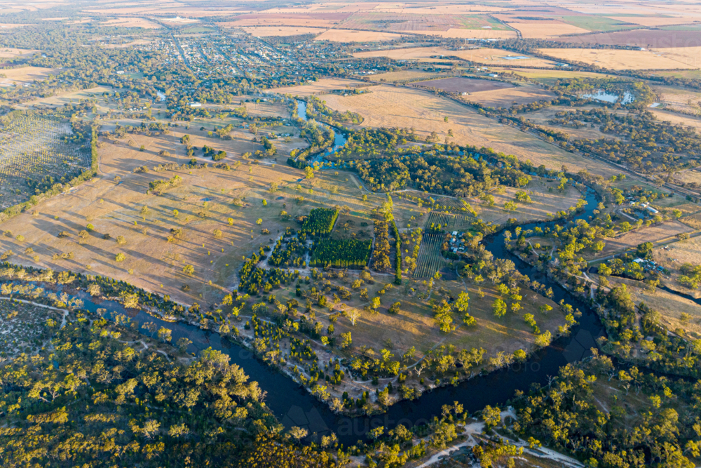 Aerial view of farmland, orchards, and winding river at sunset - Australian Stock Image
