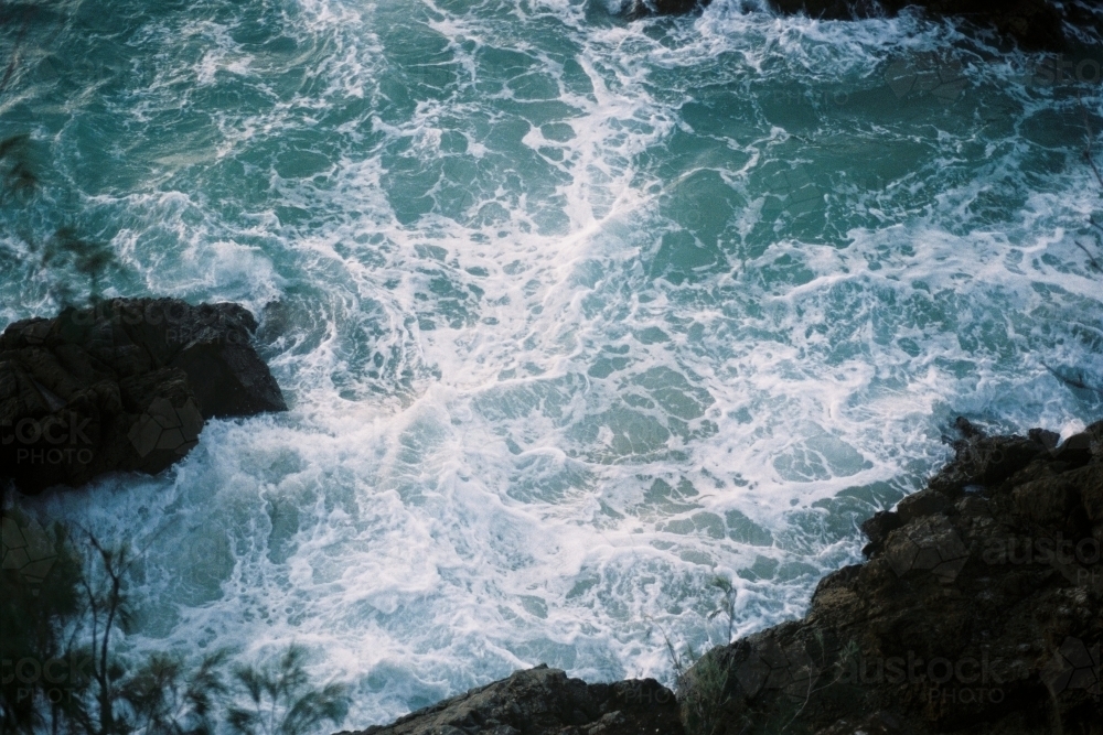 Aerial view of foam from waves hitting rocks - Australian Stock Image