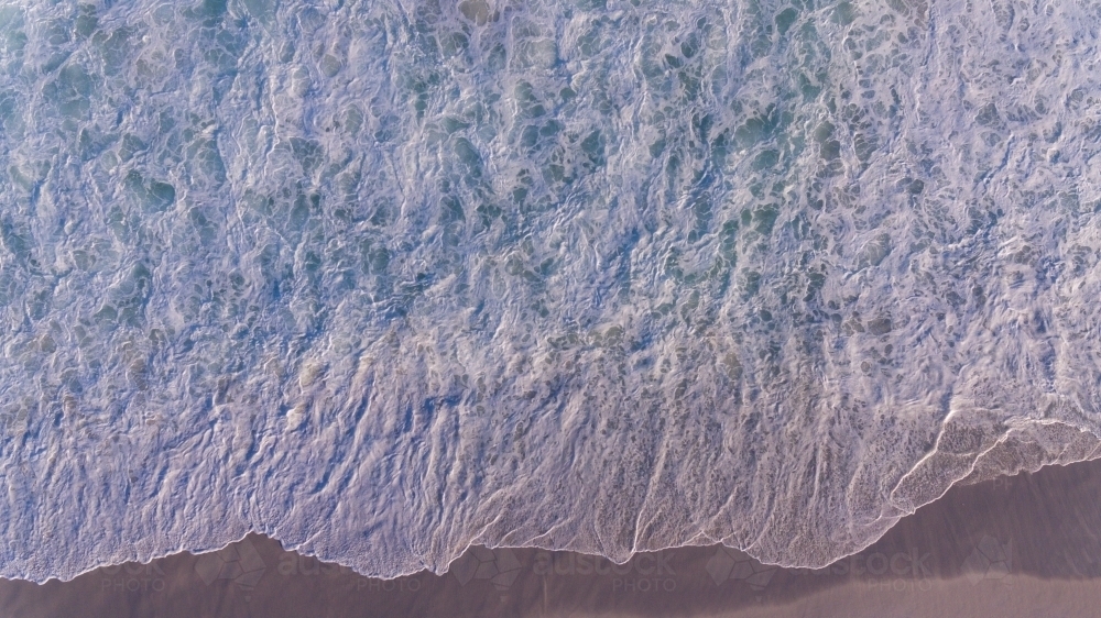 Image of Aerial view of foam from waves on the shore looks like a lacy ...