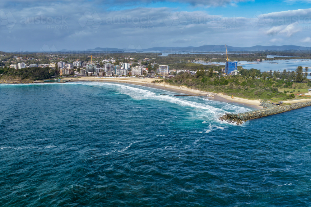 Aerial view of Forster Main Beach and the surrounding township featuring a stranded sailboat - Australian Stock Image