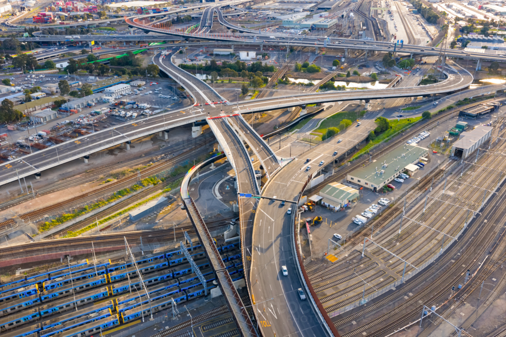 Aerial view of freeways, traffic and a network of railway tracks and carriages in a major city - Australian Stock Image