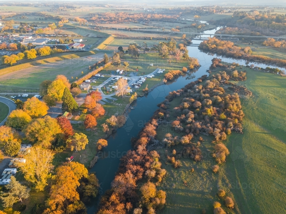 Aerial view of golden trees lining the banks of a river in Autumn - Australian Stock Image