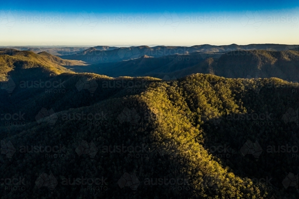 Aerial view of green mountains a in clear blue sky - Australian Stock Image