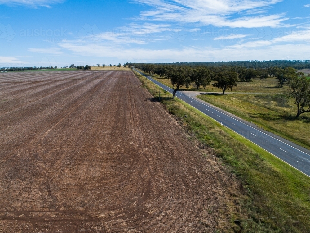 Image of aerial view of harvested crop paddock and rural country road Austockphoto