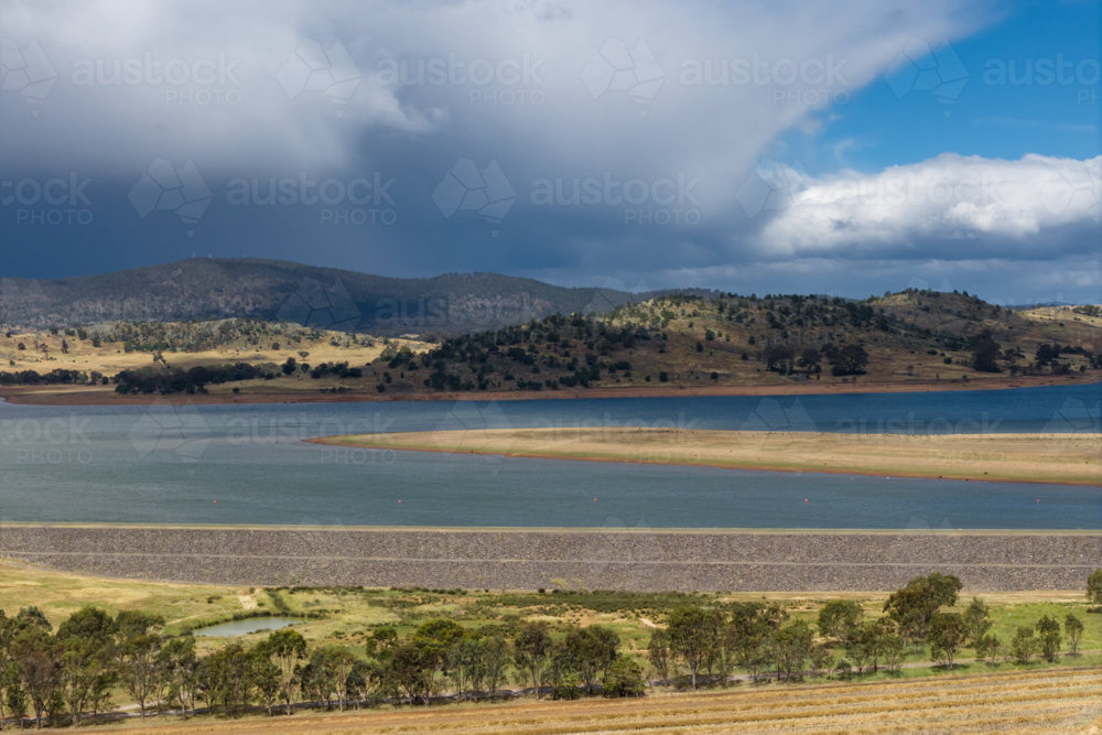 Aerial view of heavy rain falling from storm clouds over an inland reservoir and distant mountain - Australian Stock Image