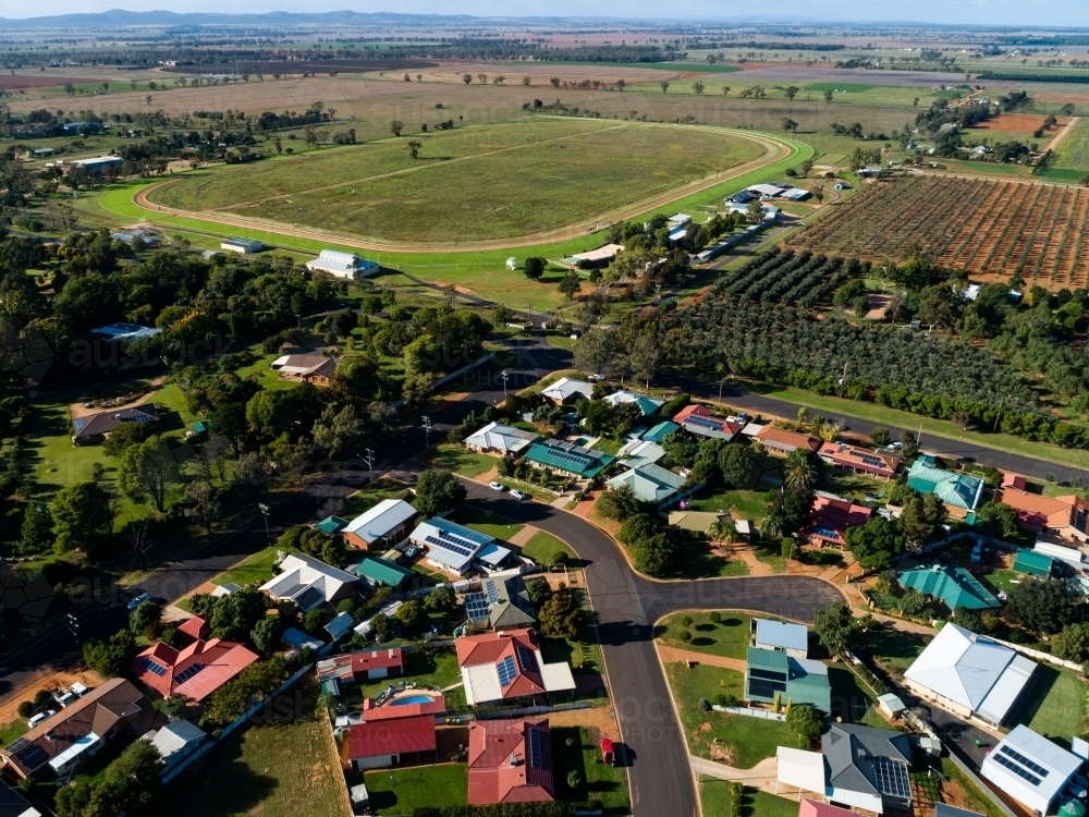 Aerial view of homes in housing area boarding edge of town, farm and race course oval - Australian Stock Image