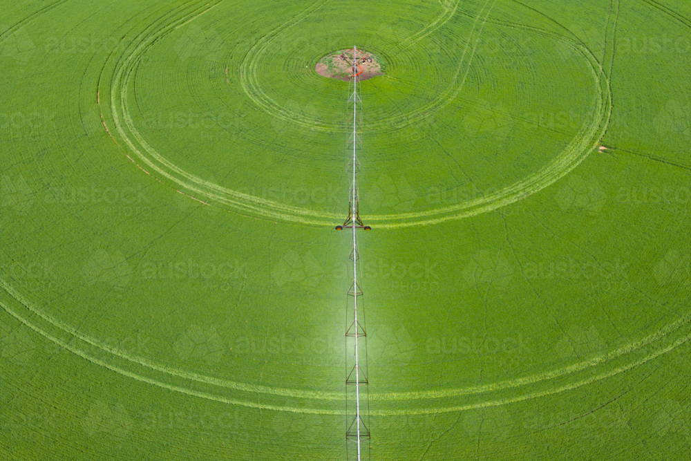 Aerial view of irrigation sprinklers mowing around a circular green field - Australian Stock Image