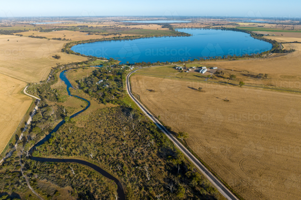 Aerial view of lake surrounded by farmland and rural settlement. - Australian Stock Image