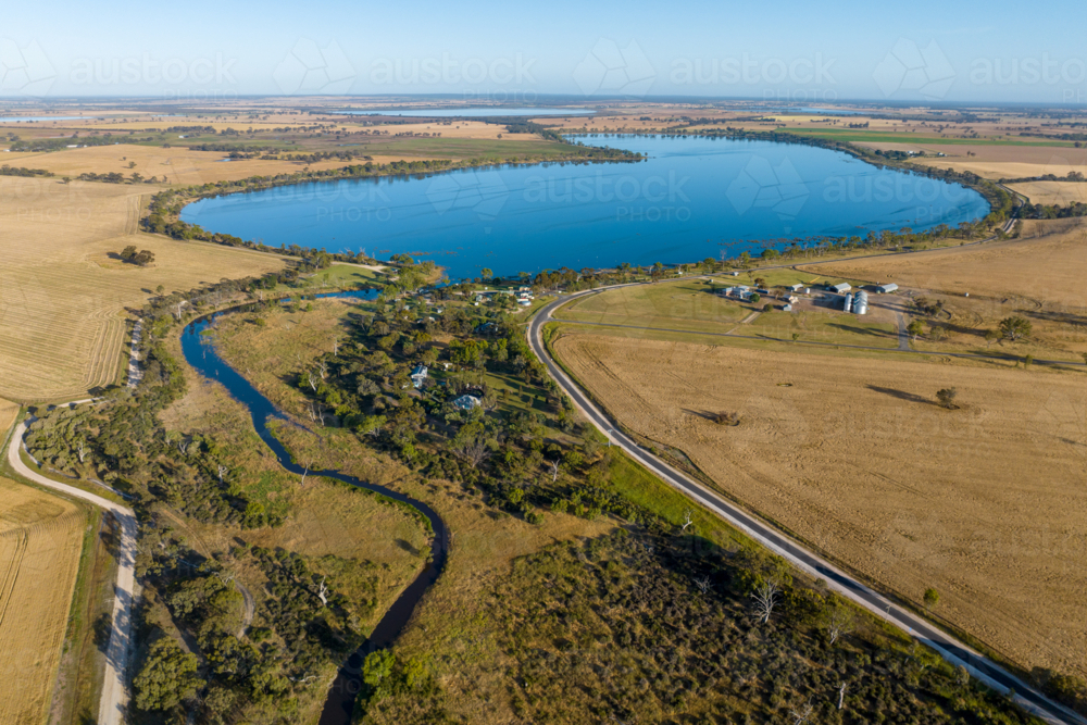 Aerial view of lake surrounded by farmland and rural settlement. - Australian Stock Image